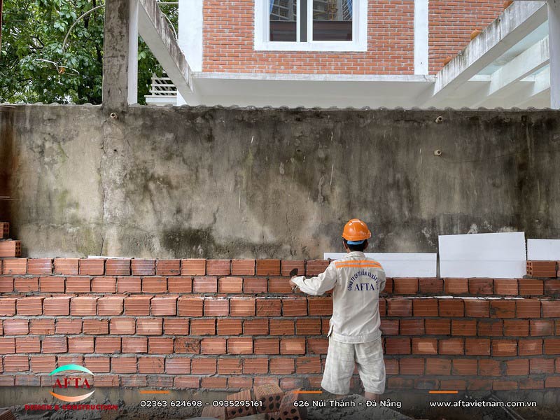 Công nhân xây tường gạch bên trong khung bê tông cốt thép của nhà đang thi công